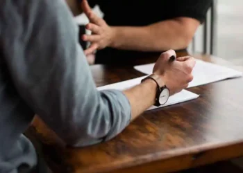 شخصان يجريان مناقشة حول وثائق قانونية على طاولة خشبية