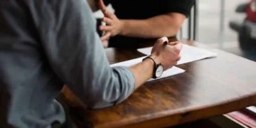 شخصان يجريان مناقشة حول وثائق قانونية على طاولة خشبية